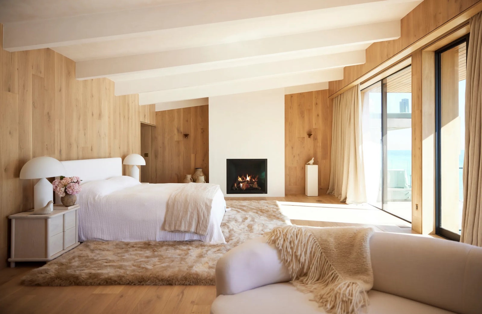 The primary bedroom at Saffron Case Homess Carbon Beach project in Malibu is lined with warm wood paneling and...