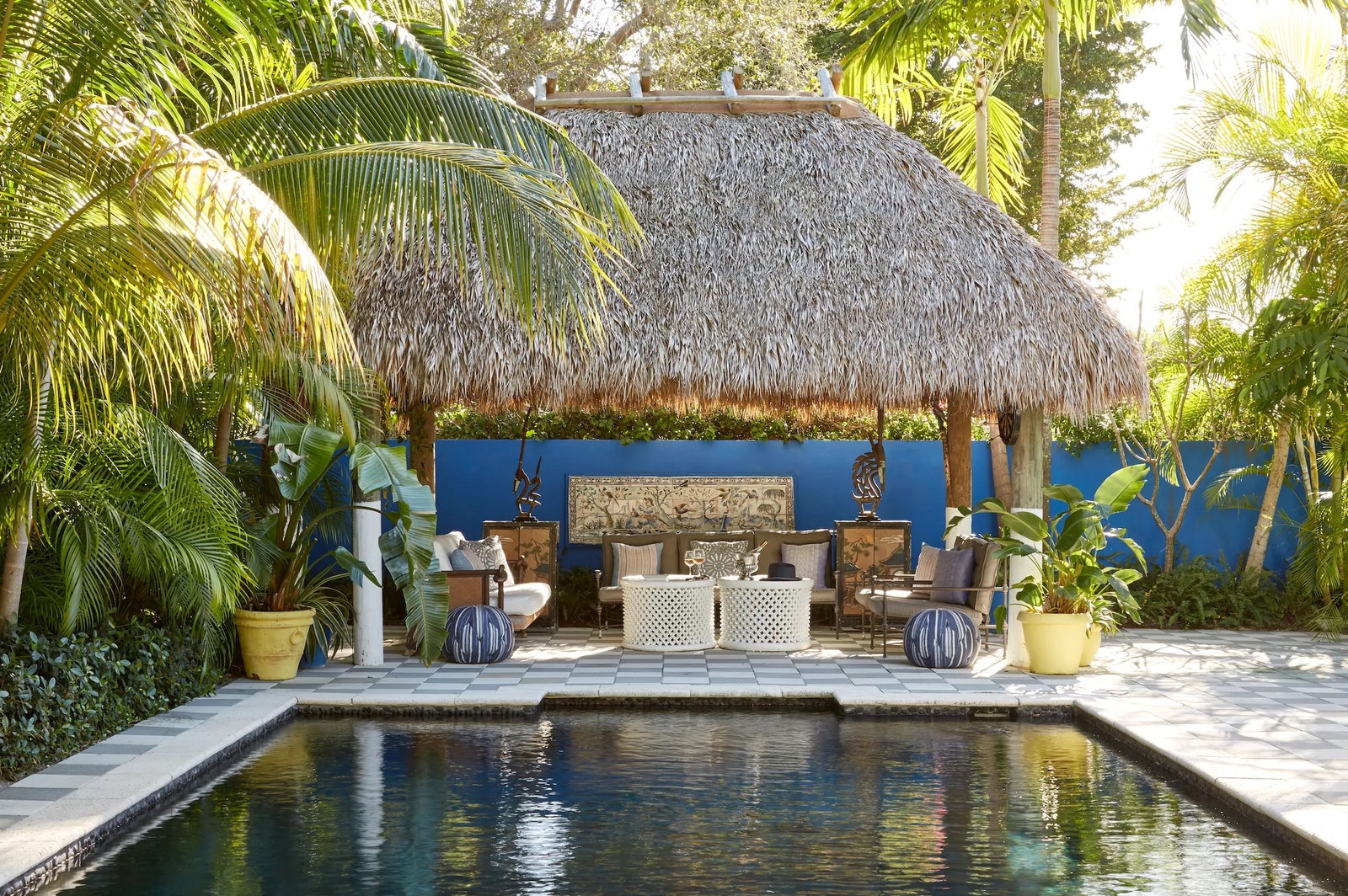 The outdoor living room in a Florida home by James Duncan is covered with a thatched roof and furnished with pieces from...