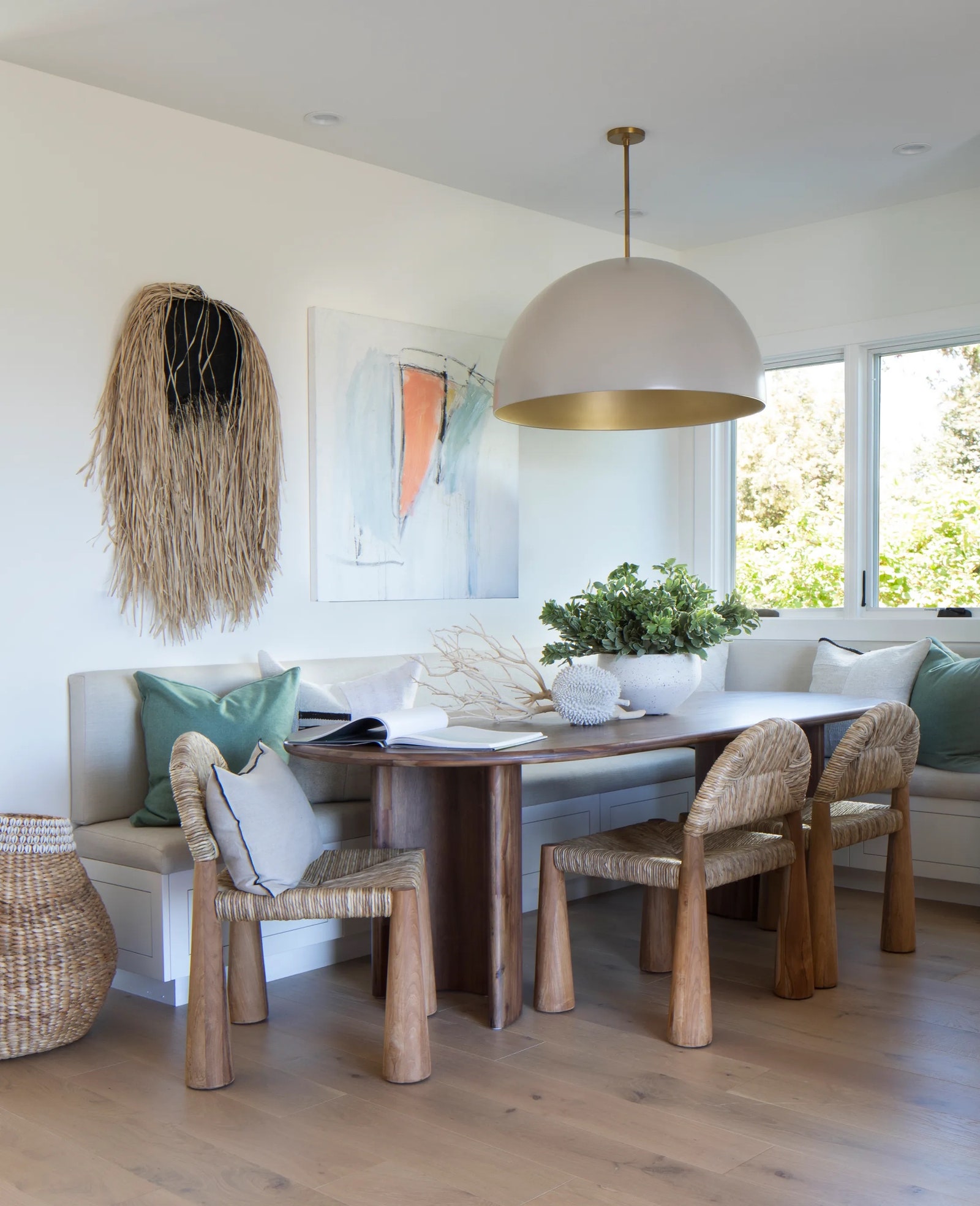 A breakfast room created by LarkPalm in a 1950s ranch in Kentfield California features a custom banquette and artwork...