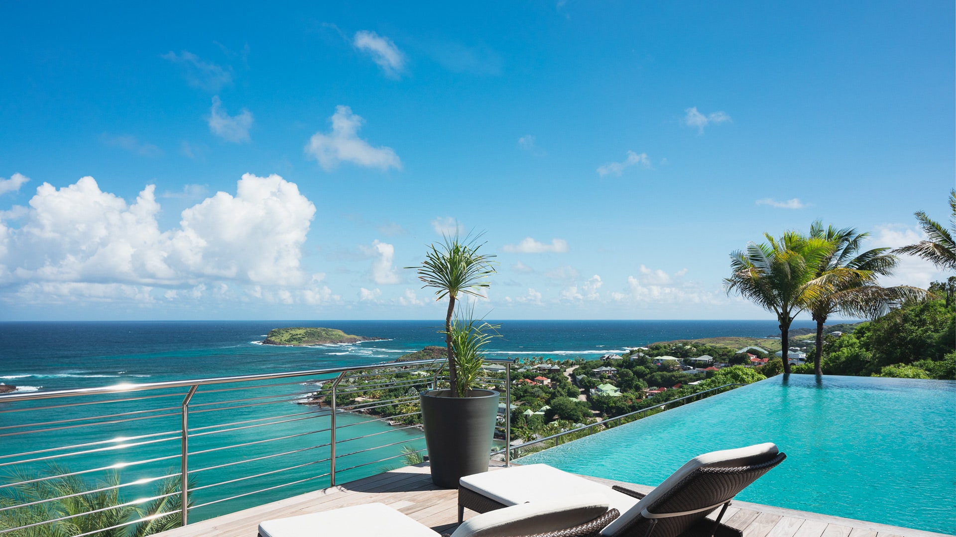 two chairs and an infinity pool on a deck overlooking the ocean