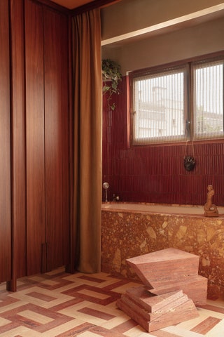 In the bath Breccia Siena marble clads the tub and the niche is covered in fluted tile by Cramiques du Beaujolais....