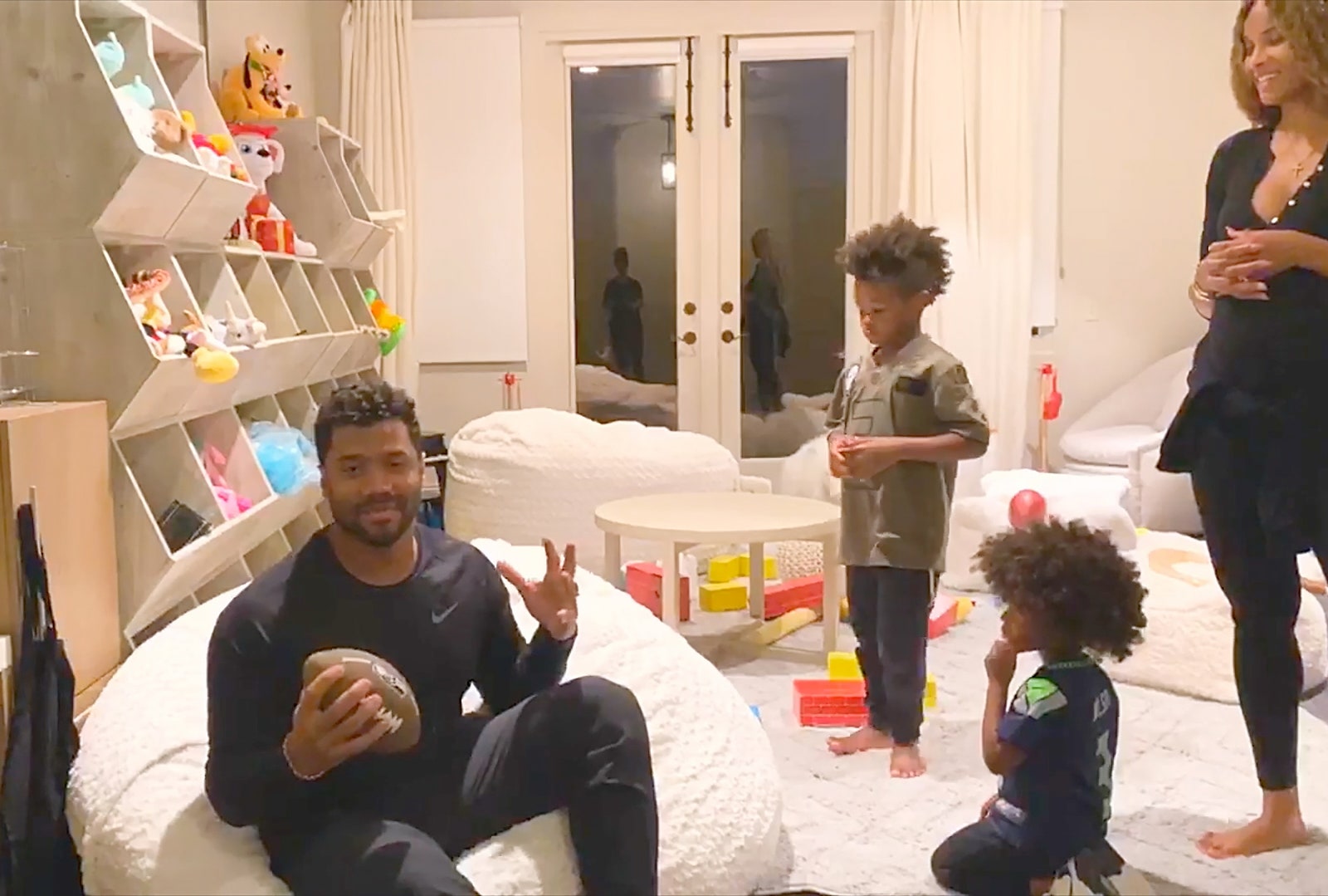 Russell Wilson Ciara and children Future and Win in a white playroom with toys and cubbies