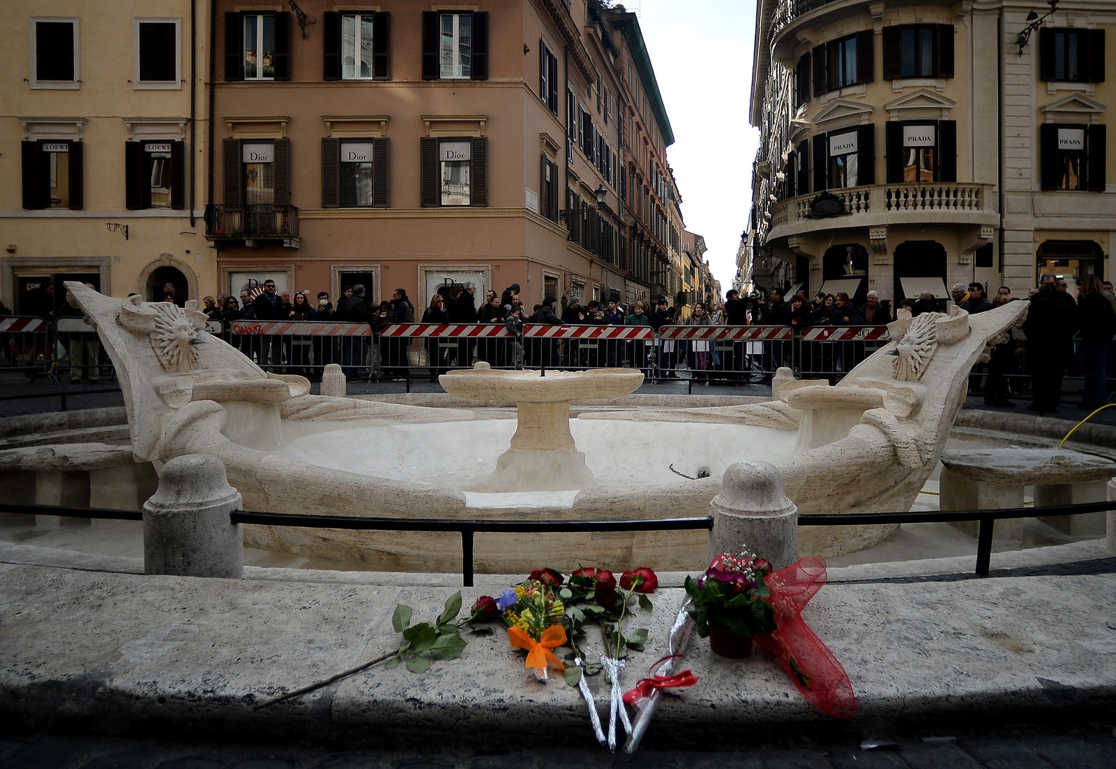 Romes Piazza di Spagna with flowers left at cordonedoff damaged fountain